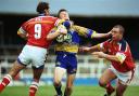 Warrington Wolves half back Lee Briers gets one round his chops from London Broncos hooker Peter Gill. Pictures by Mike Boden