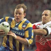 Greg Mackey looks to escape the clutches of Wigan's Shaun Edwards