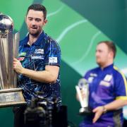 Luke Humphries lifting the World Darts Championship trophy in front of Luke Littler earlier this month