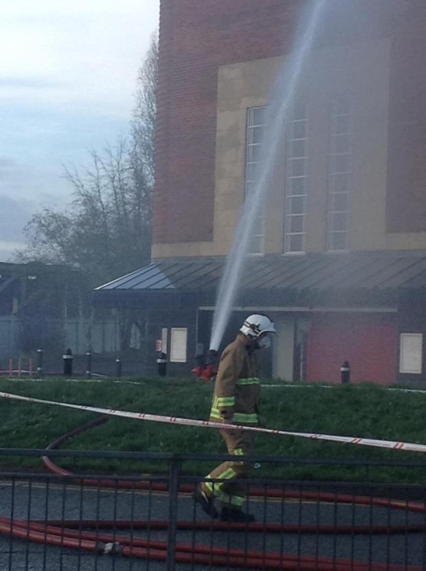 A firefighter walks past the scene in a mask.
