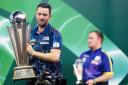 Luke Humphries lifting the World Darts Championship trophy in front of Luke Littler earlier this month