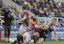 Jack Hughes is brought down by Wigan's Joe Burgess. Picture by Mike Boden