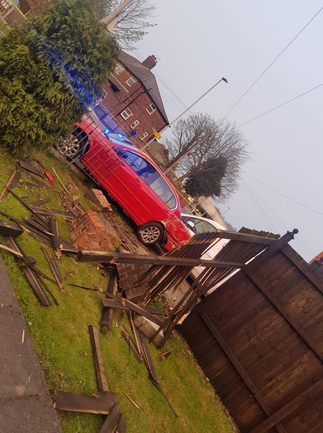 The scene after the red Jaguar car Peter Thomas was driving crashed into a garden wall, gate and fence