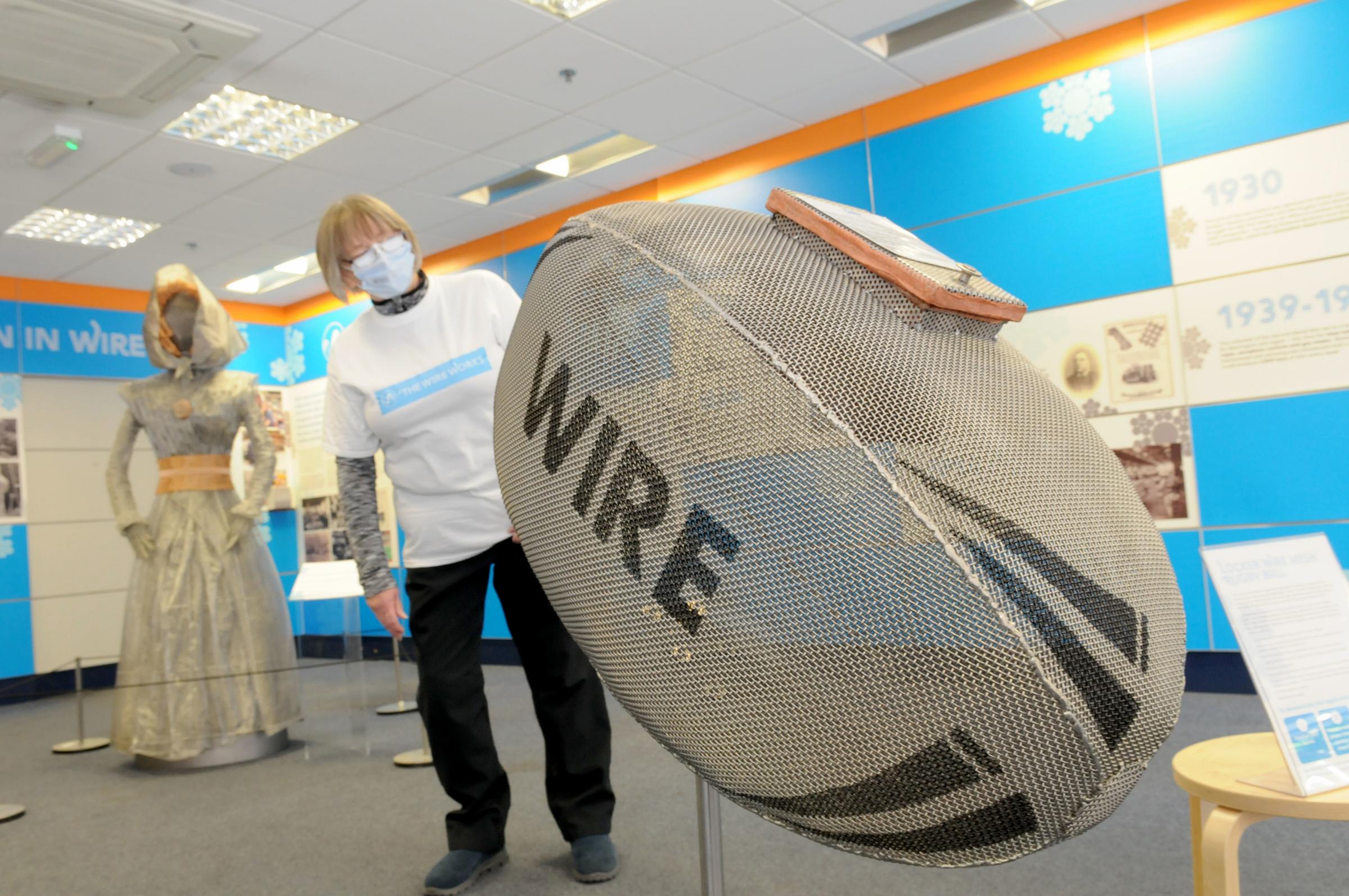 A volunteer looks at the Wire Works exhibition of a Wire ball