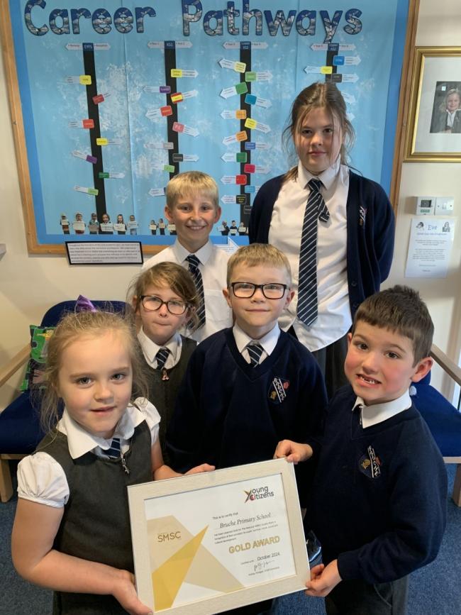 Bruche Primary School pupils with the school's gold level mark