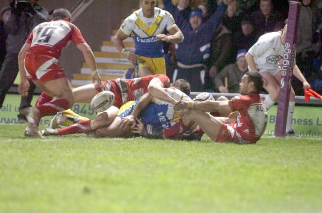 Who is the Warrington Wolves player lay on the ground after being tackles by Wigan players? Picture: Mike Boden