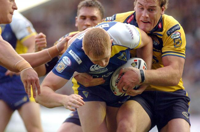 Who is the Warrington Wolves player with his head bowed in the tackle? Picture: Mike Boden
