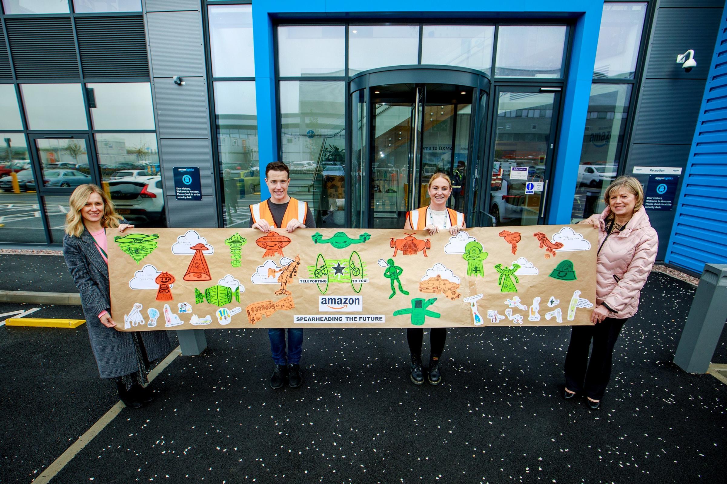 Amazon Warrington staff with the banners designed by schoolchildren from the town