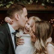 Newlyweds Rachel and Matthew share a kiss on their wedding day with daughter Willow